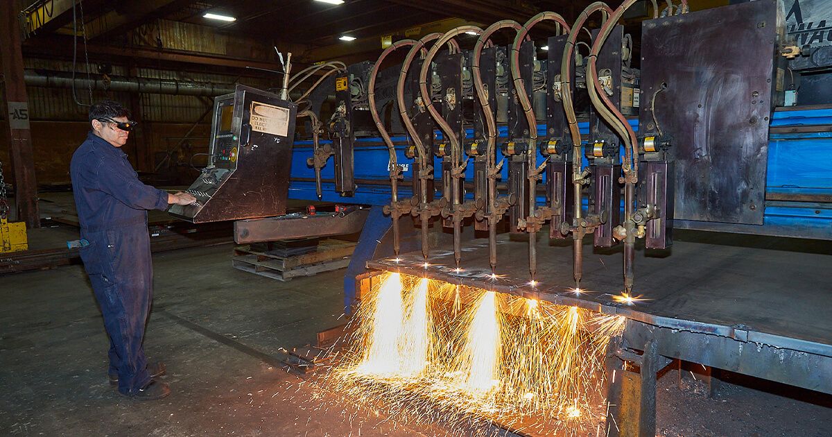 Amber Steel worker operating flame cutting machine.